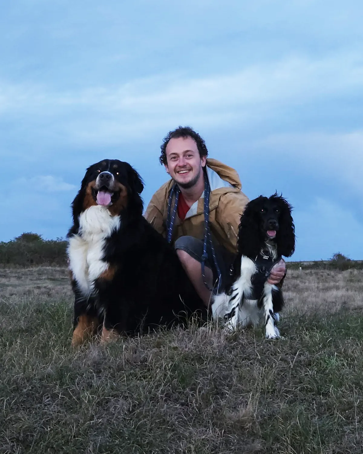 Jason crouching in the dunes next to Coco, a working cocker spaniel